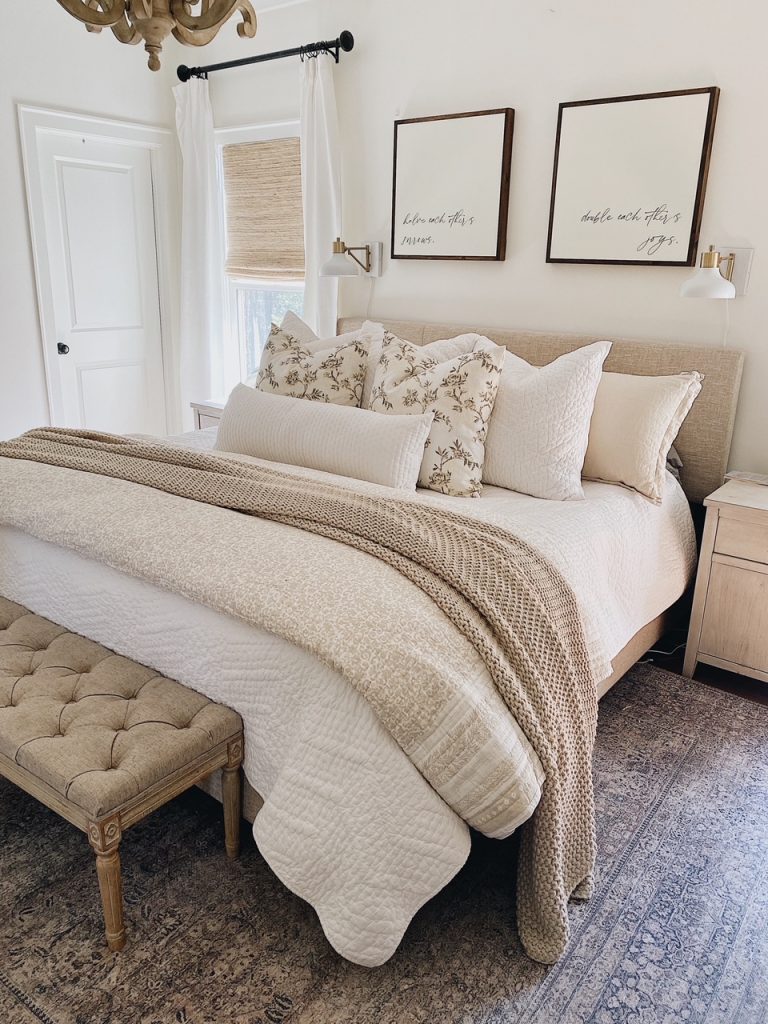 Layered bed with neutral linens, throws, and soft textures